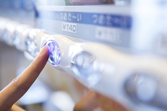 自動販売機のボタンを押す人の手元