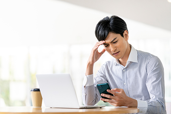 スマホを見て悩んでいる男性